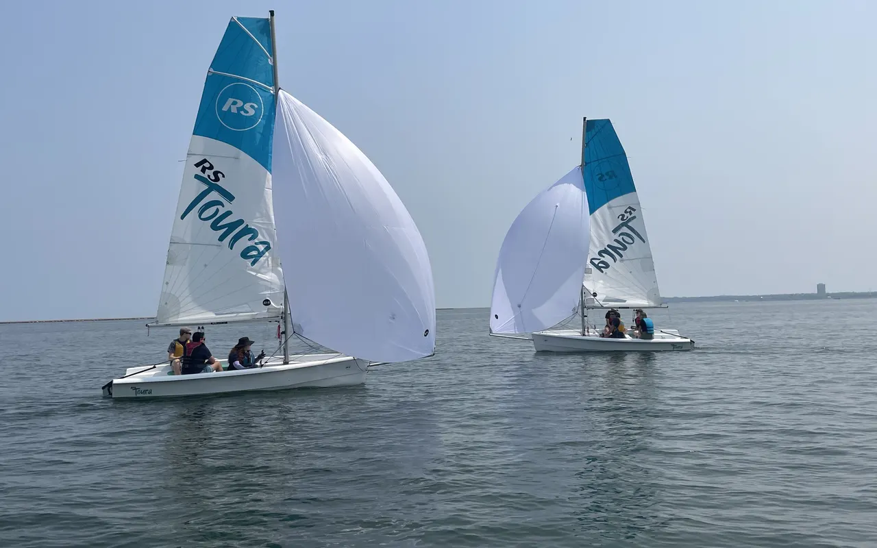 Two small keelboats on a beam reach flying white asymmetric spinnakers
