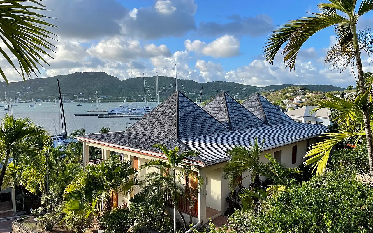 Palm trees and a historic building above English Harbour, Antigua, with yachts beyond