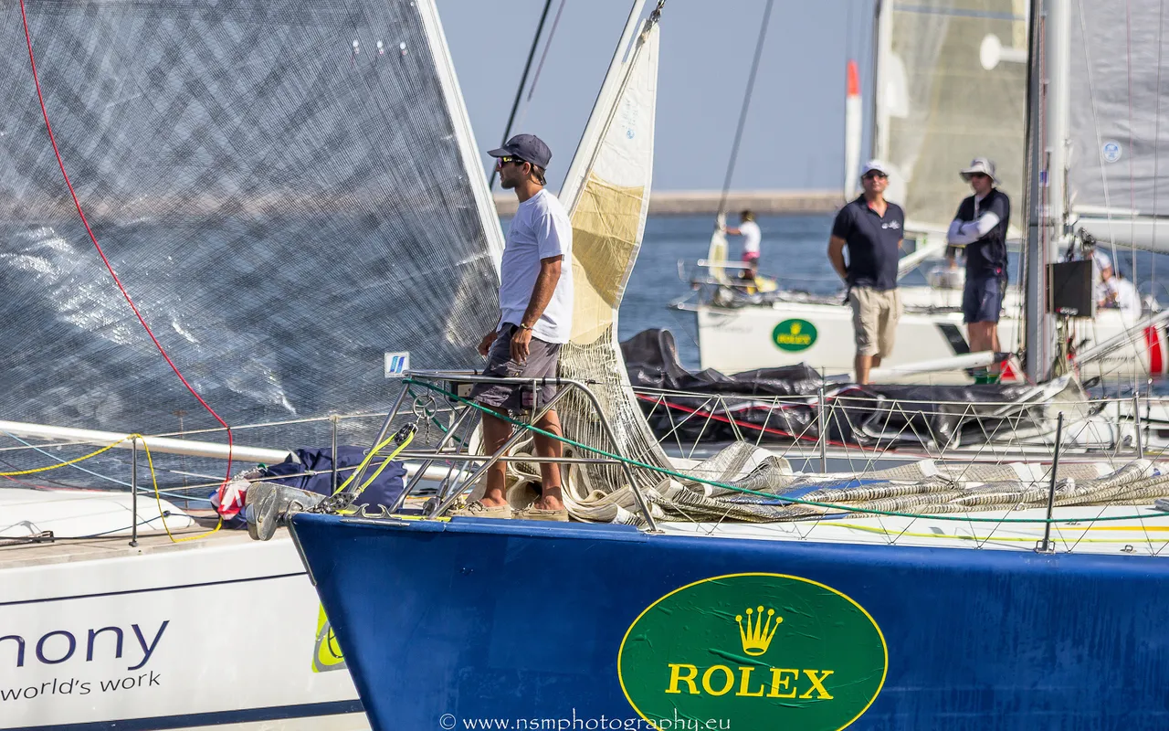 Crew member on the bow of a racing yacht in a crowded Grand Harbour, Malta