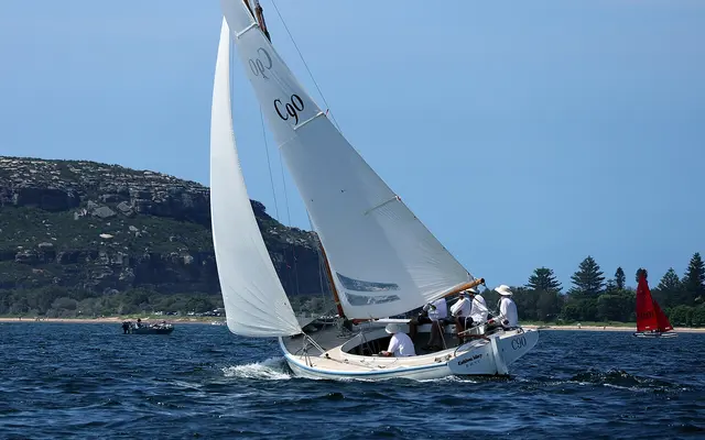 Eine klassische Yacht segelt auf dem Pittwater vor bewaldeten Landzungen