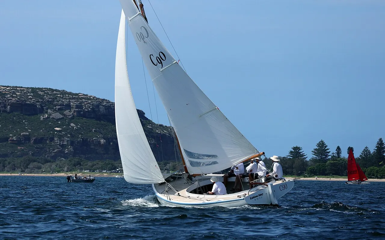 A classic yacht sailing on Pittwater with wooded headlands behind