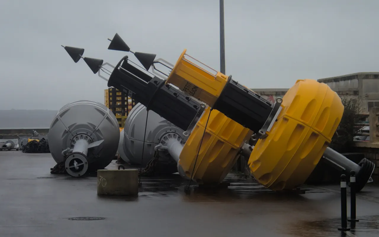Several yellow and black cardinal buoys lying on a quay waiting to be deployed