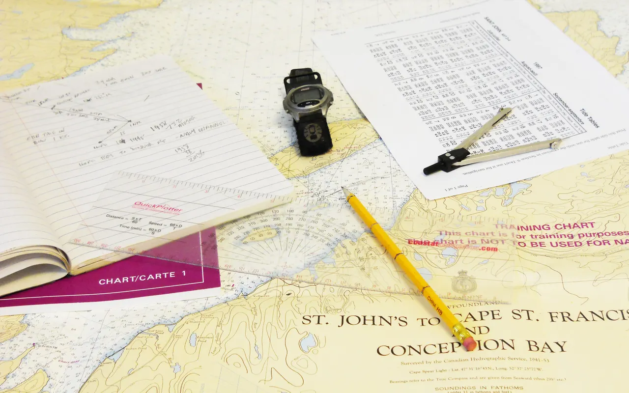 A chart of a bay with a pencil, dividers and a page of navigation notes laid on top