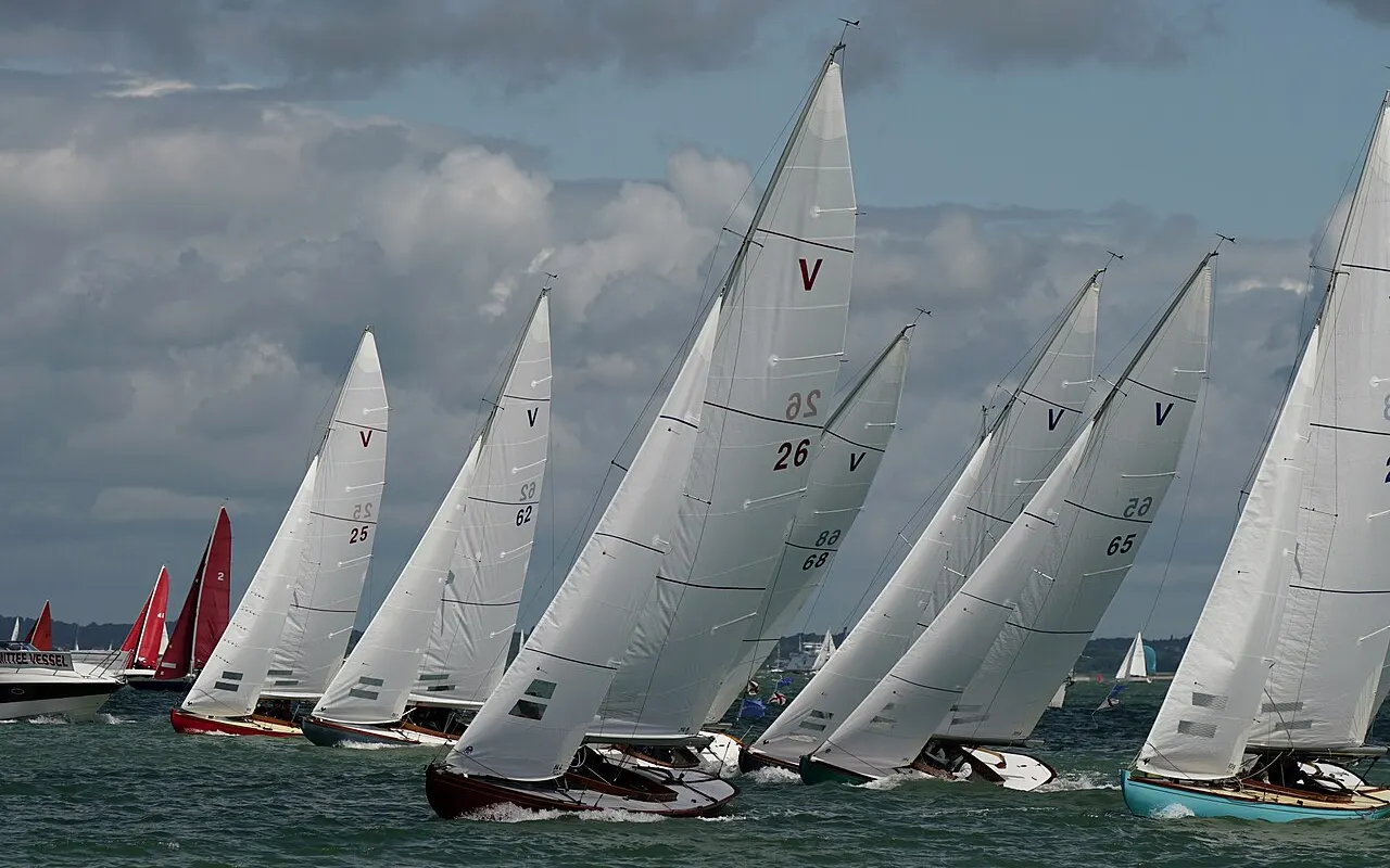A fleet of yachts with white sails racing at Cowes Week