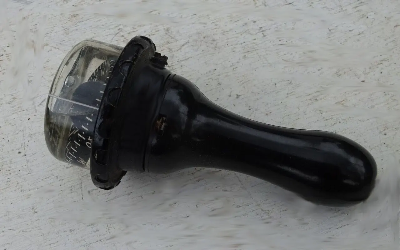 A Sestrel hand-bearing compass with a domed card and a black handle