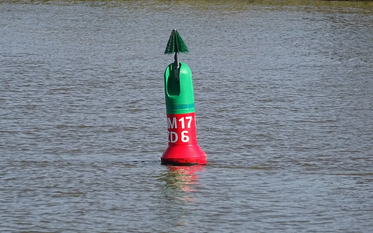 A green buoy with a red band marking where a channel divides