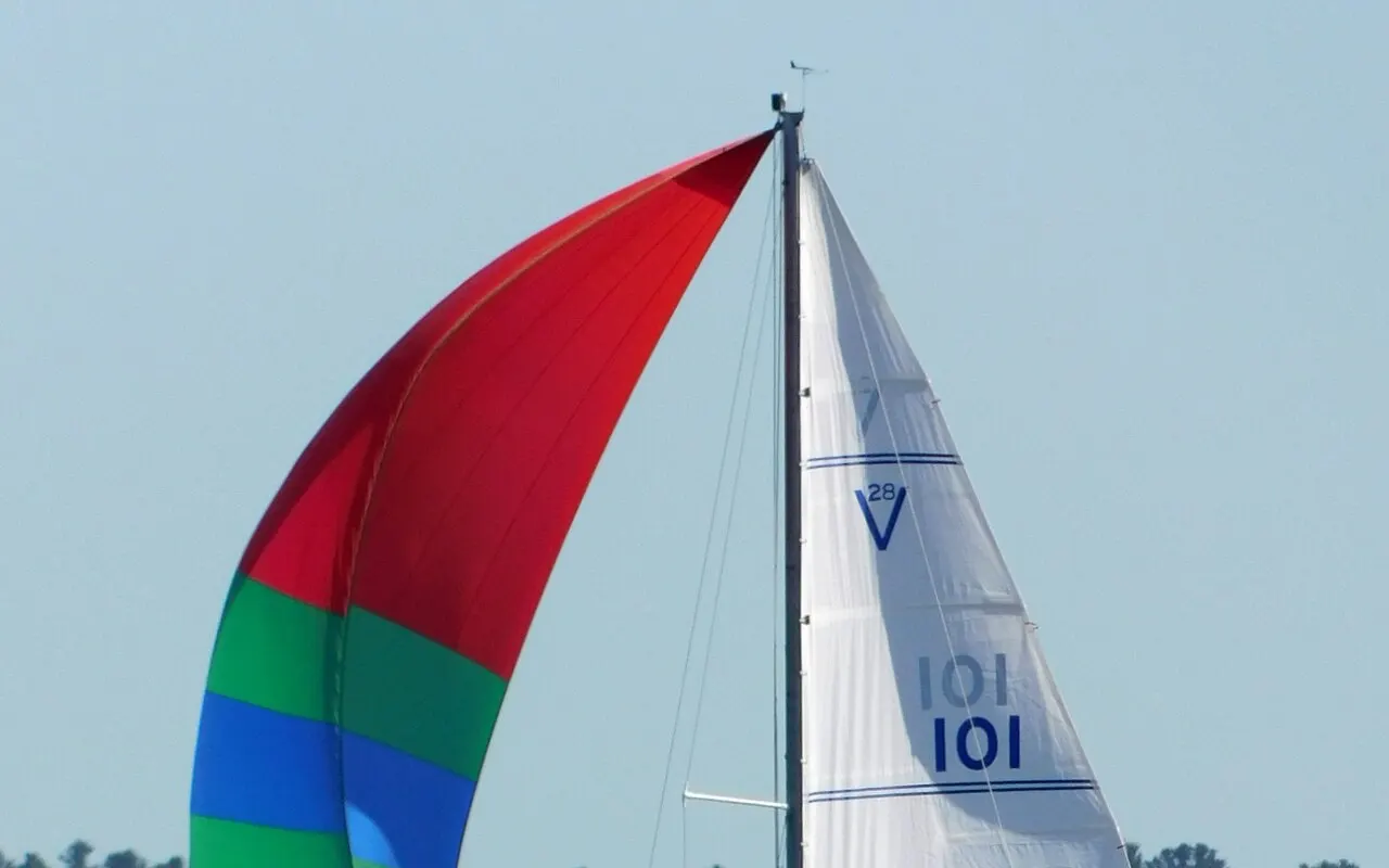 Un petit voilier de croisière au portant sous spinnaker coloré