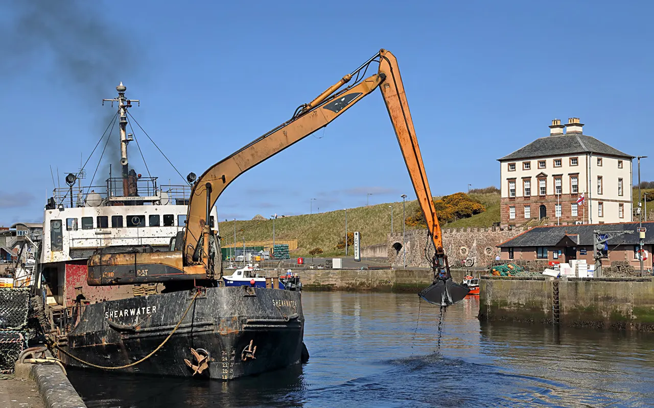 Una draga con un largo brazo excavador trabajando en un puerto
