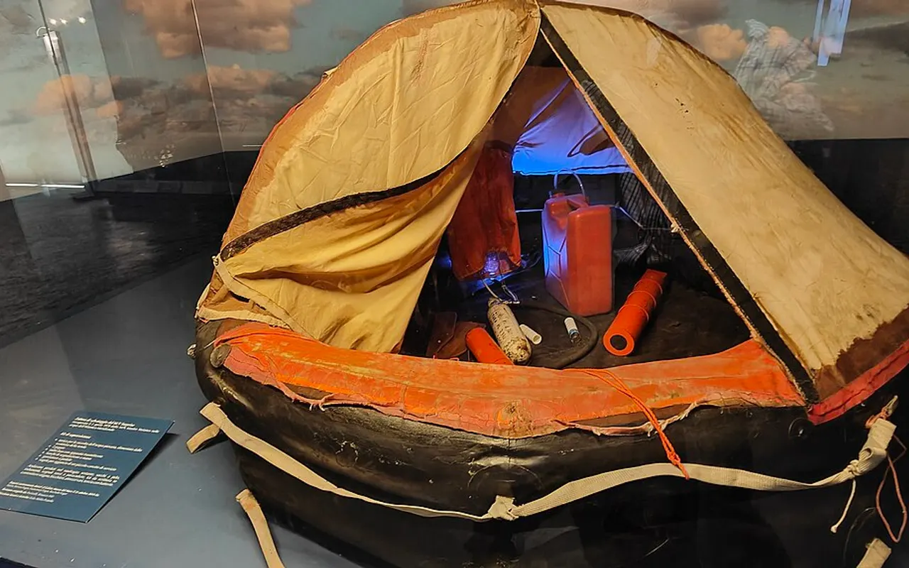 An inflated liferaft with its canopy open, showing the survival pack