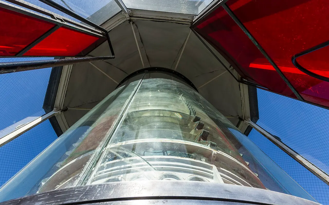Mirando hacia arriba dentro de la linterna de un faro con paneles de cristal de colores