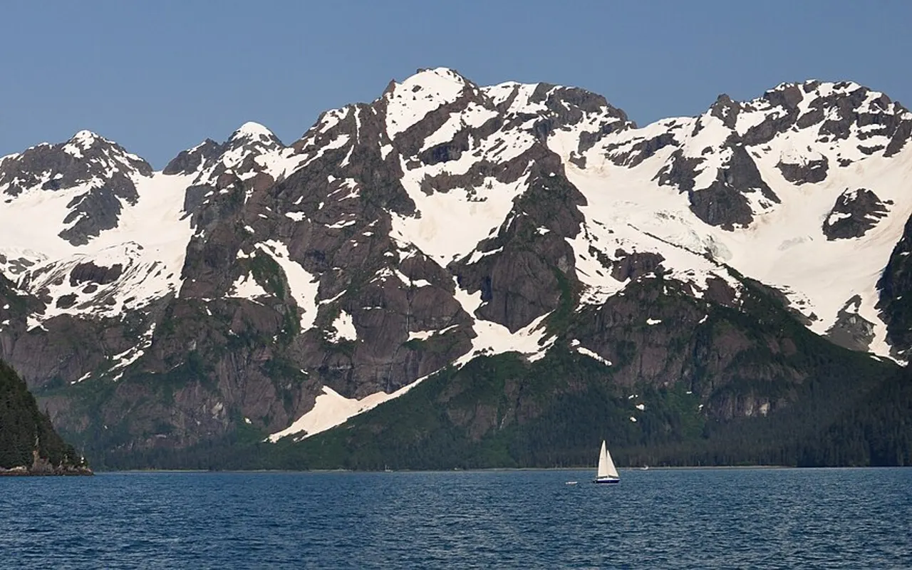 Un petit voilier sous des montagnes enneigées dans une baie abritée