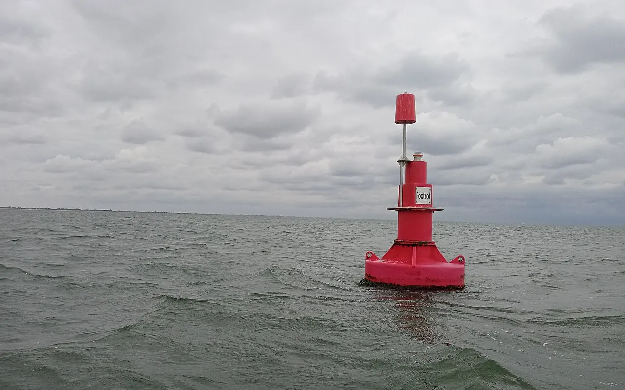 Una boya roja con forma de lata de babor en el mar