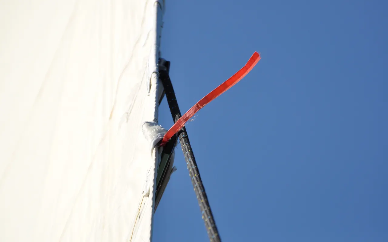 Un penon rouge flottant depuis le bord d'une voile