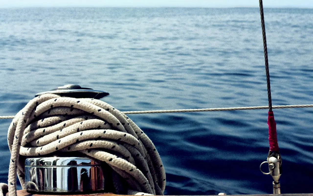 Vueltas de cabo en el winche de un yate de vela con el mar detrás