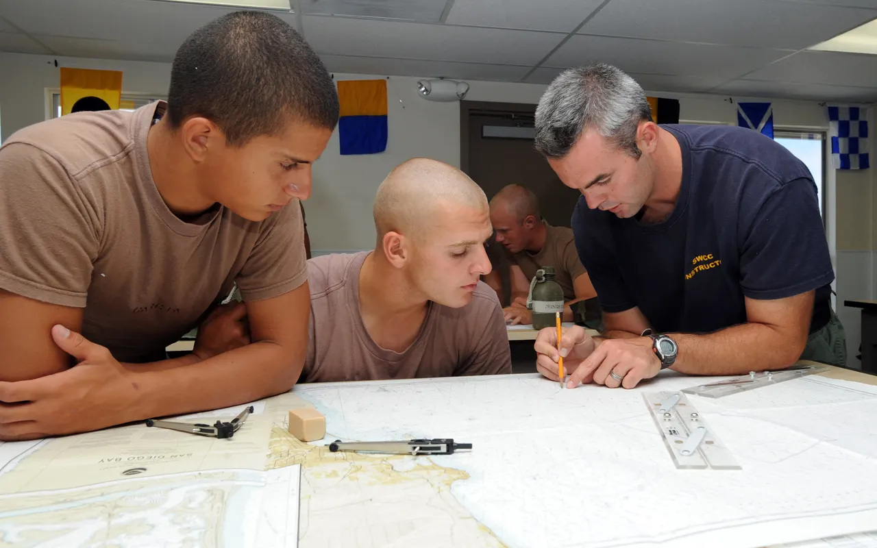 An instructor showing students how to lay out a track on a paper chart in a classroom