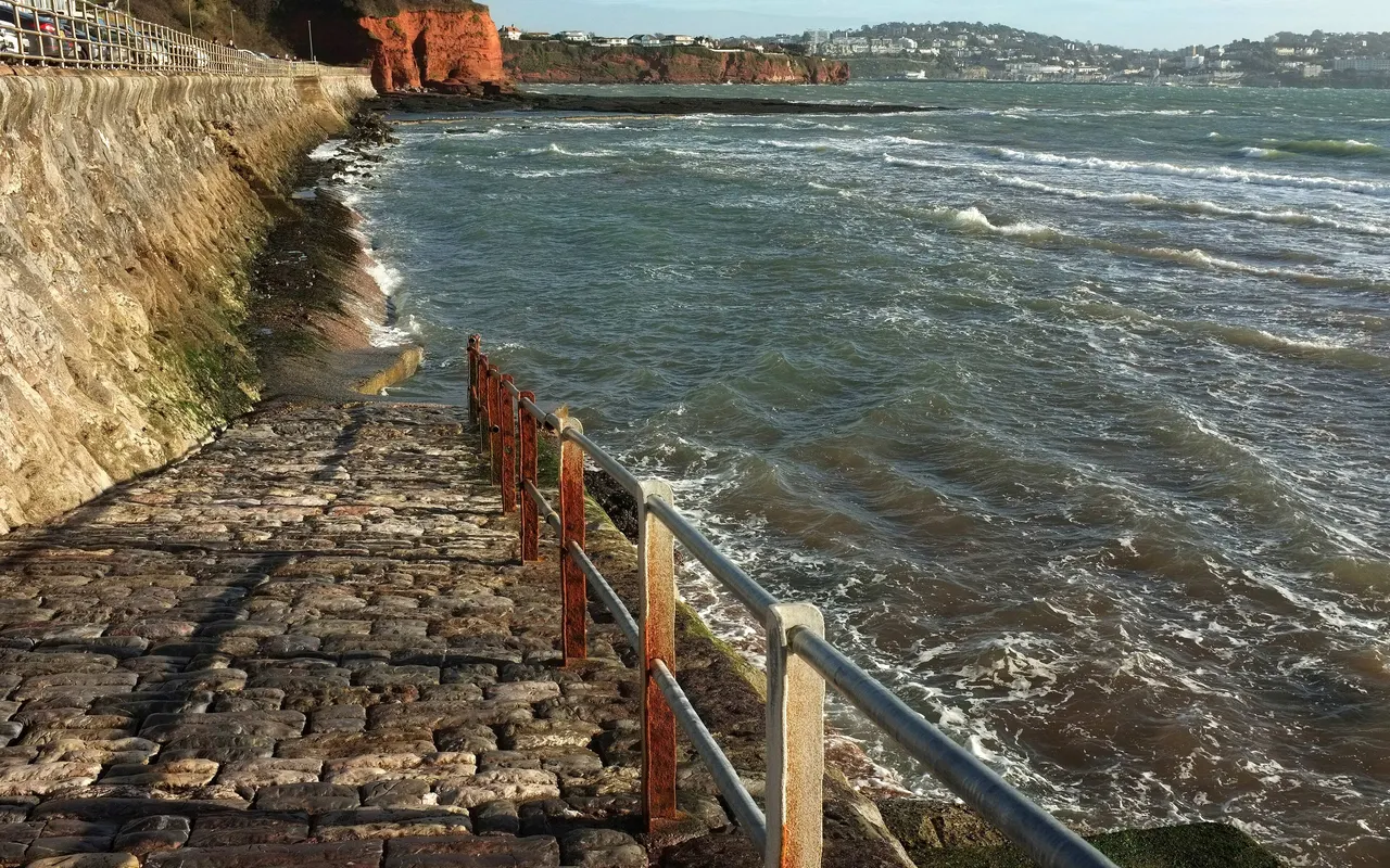 A sea wall and slipway at Preston Sands, Devon, with water lapping at the base at neap tide
