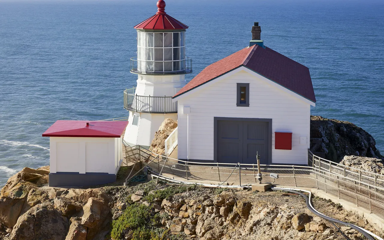 Point Reyes lighthouse, a white tower with a red roof on a rocky headland above the Pacific
