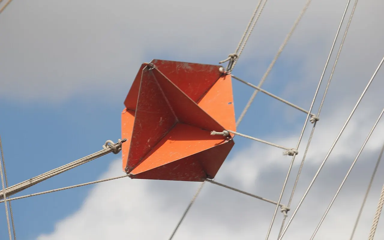 An orange octahedral radar reflector hoisted in a sailing yacht's rigging