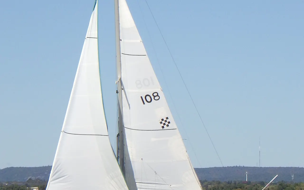 A small sloop sailing upwind under mainsail and jib in a fresh breeze