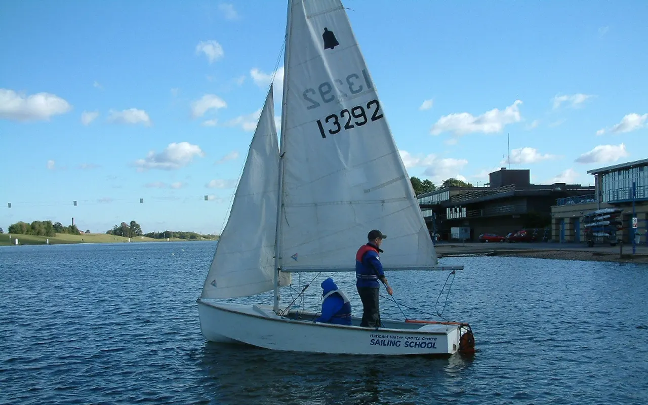 A sailing school dinghy with an instructor and student on calm water