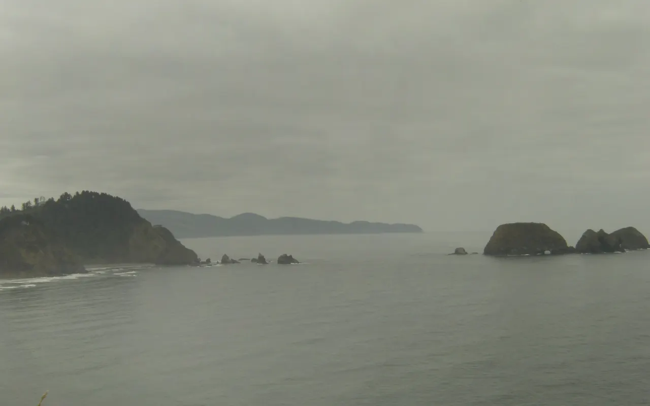 Sea fog over grey water with rocky islands fading into the mist