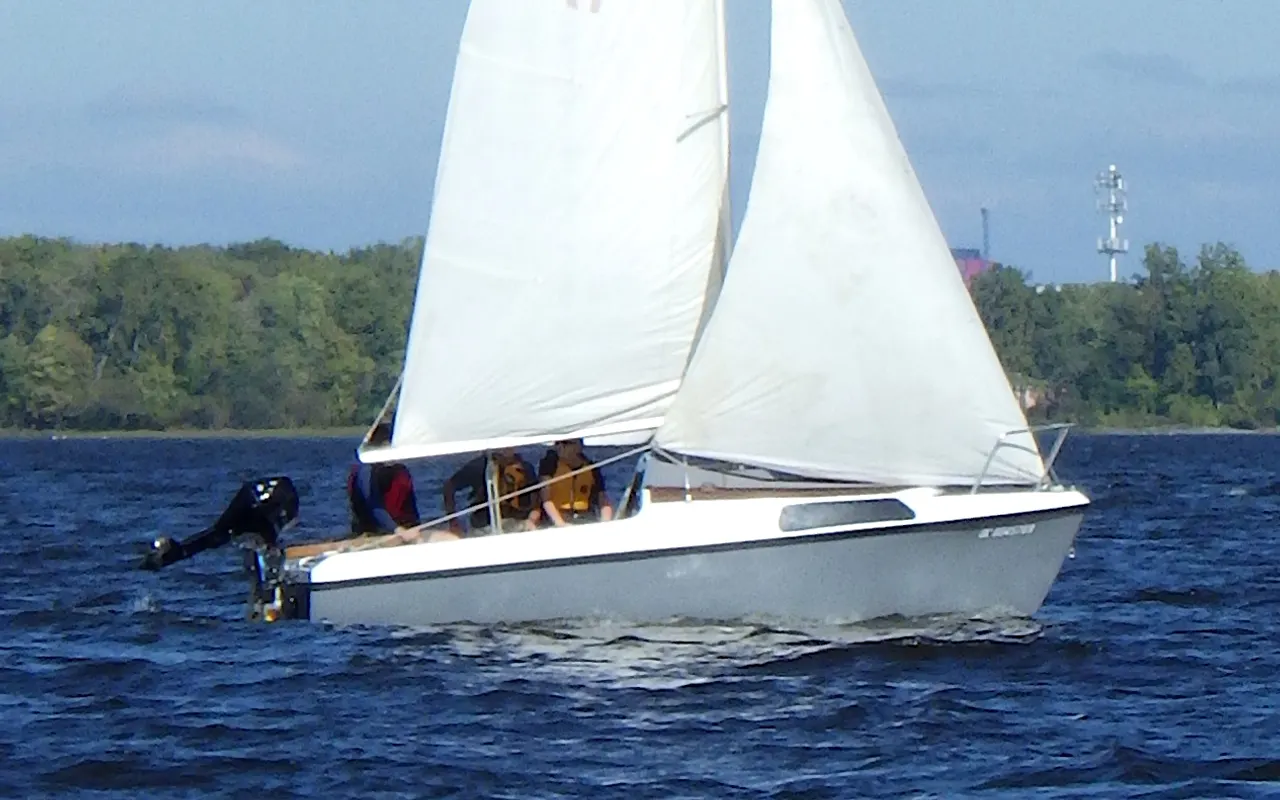 A small sloop sailing close-hauled with its mainsail and jib sheeted in