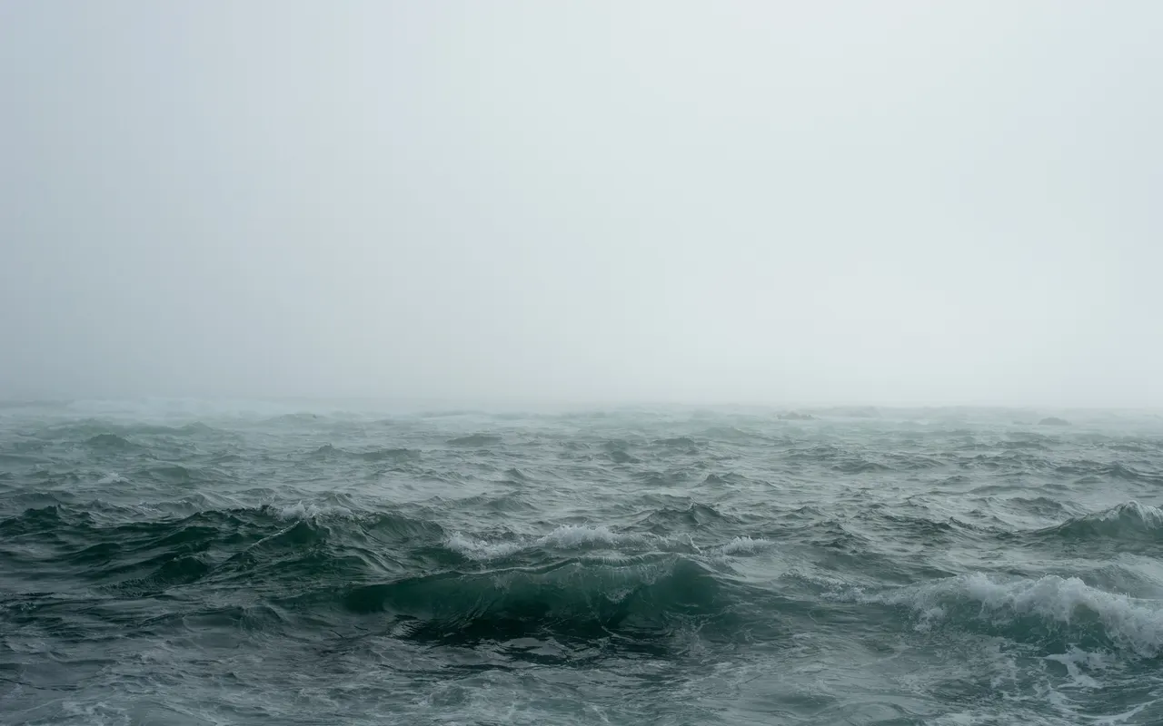A rough sea of breaking waves and spray under a dark sky