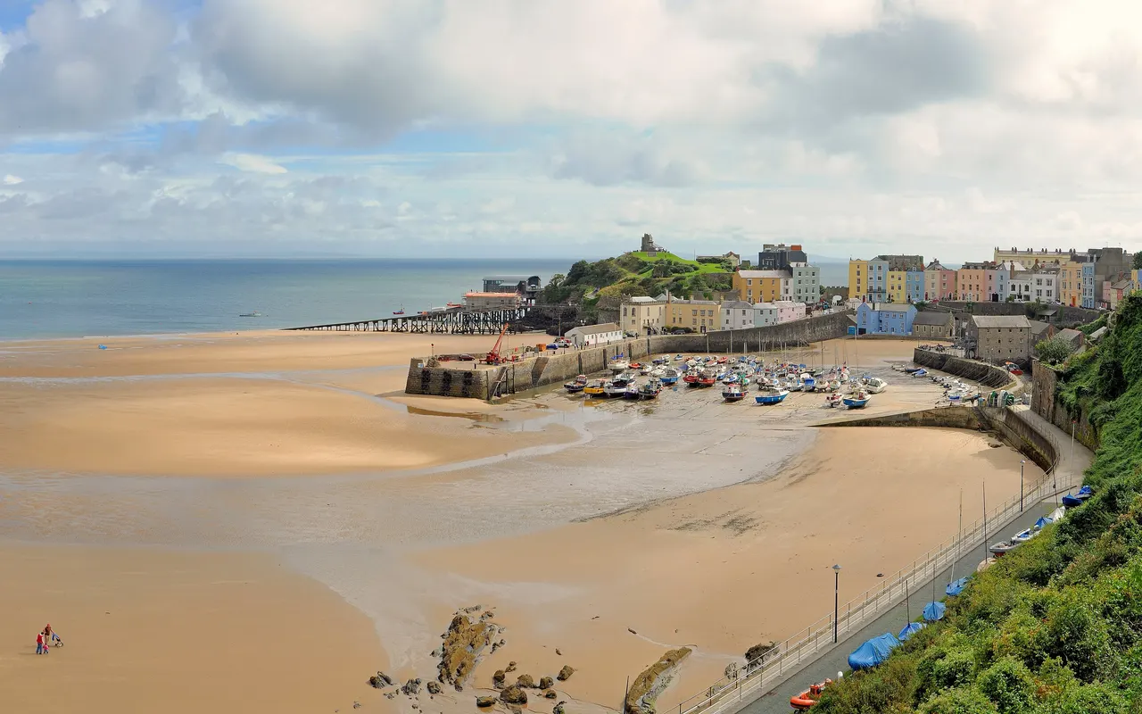 A wide sandy beach and harbour at Tenby, Wales, at low tide