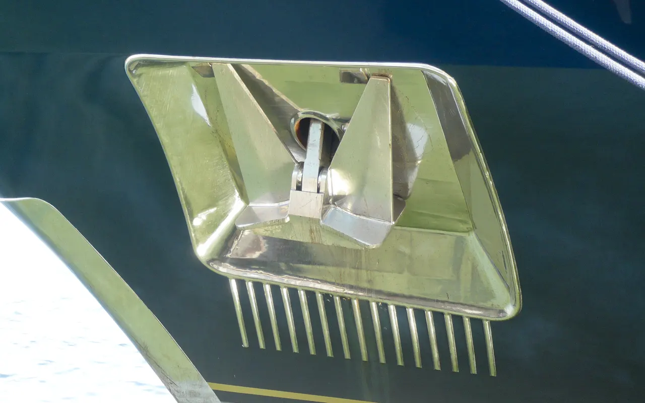 A stainless steel anchor stowed on the bow roller of a yacht