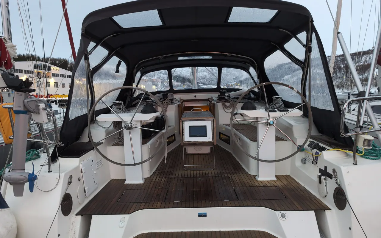 The cockpit of a modern sailing yacht with two wheels, winches and instruments under a sprayhood