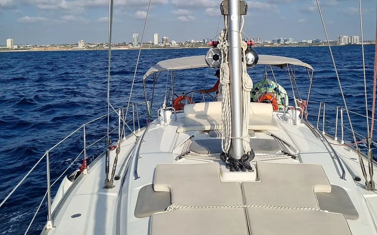 Looking aft from the bow of a sailing yacht over the deck to the mast, guardrails and cockpit