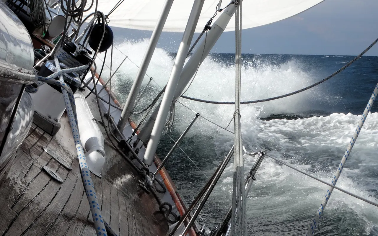 View from the deck of a heeling sailing yacht with the sea rushing past