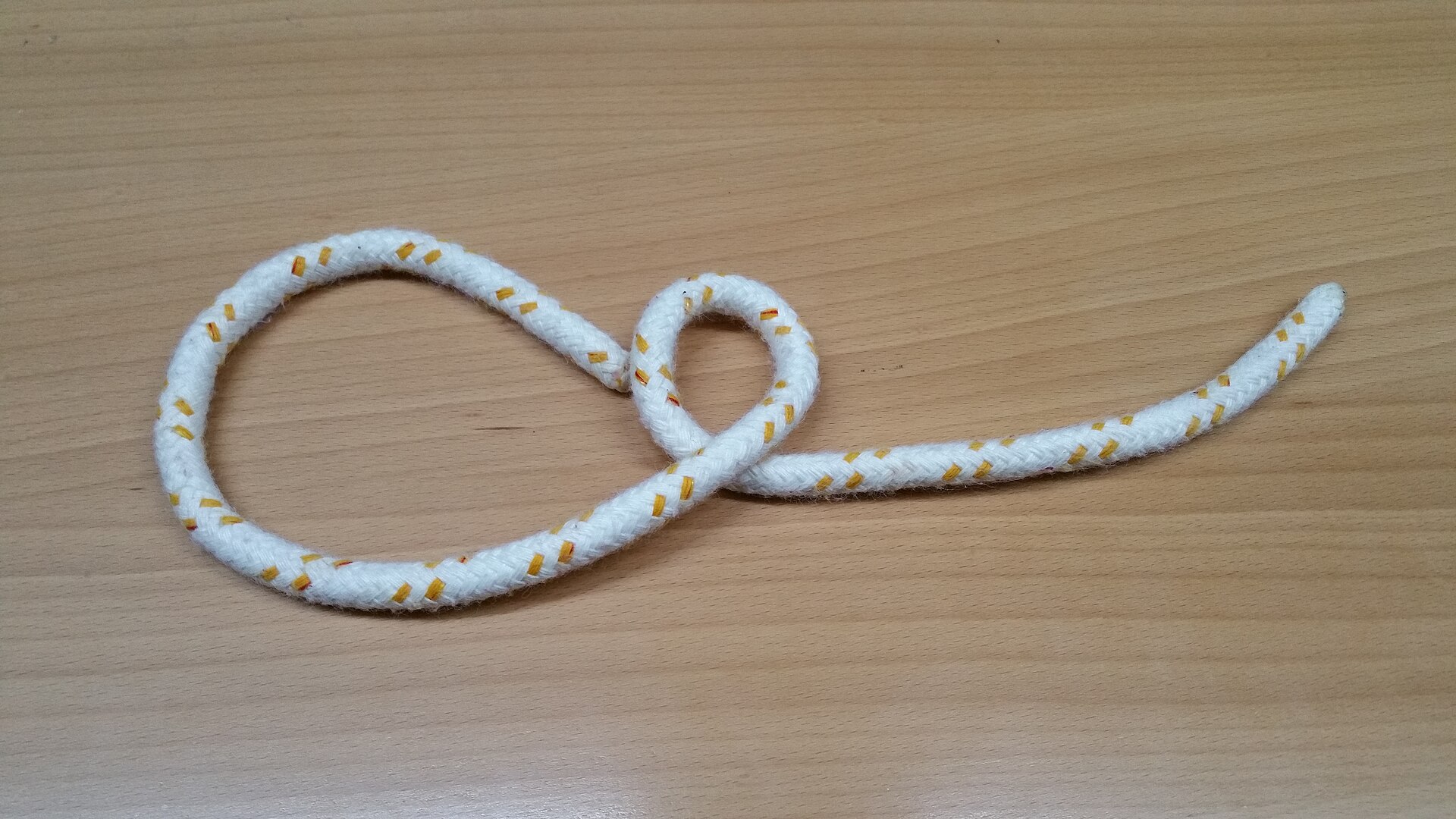 A small overhand loop formed in white rope, tail leading off to the right
