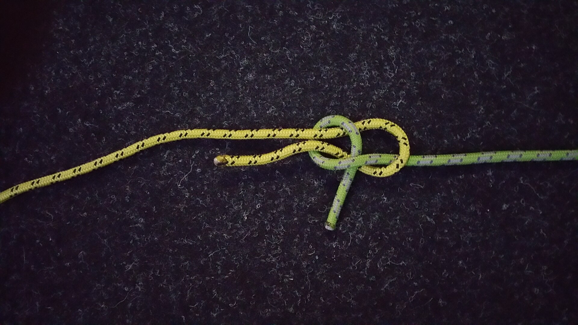 The green rope tucked under itself to form the sheet bend