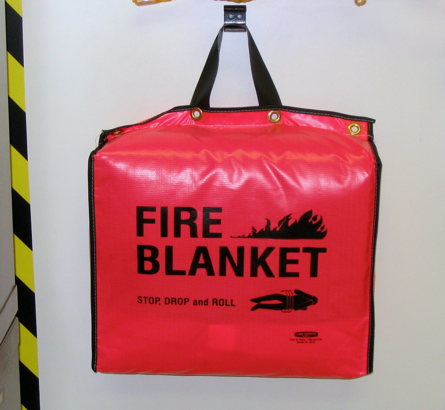 Fire blanket in its holder, ready to pull by the tapes