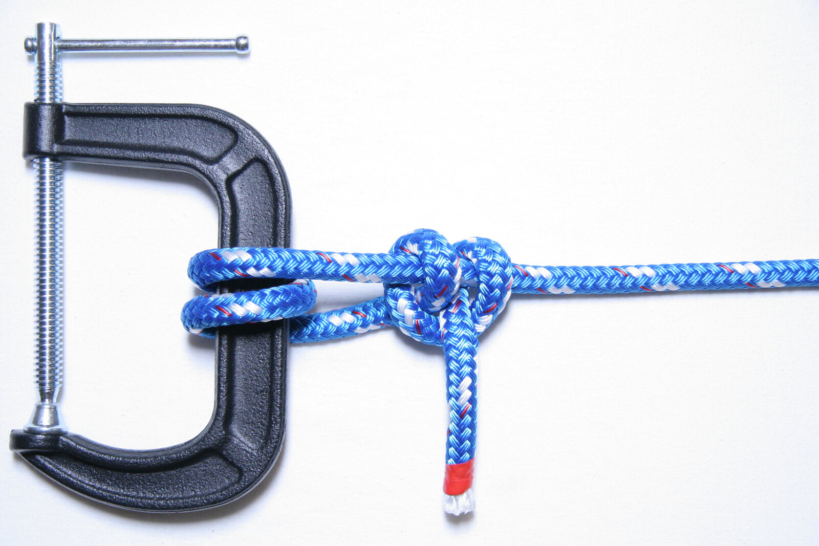A round turn and two half hitches tied in braided rope around the bar of a clamp: the round turn grips the bar and the two half hitches lock the standing part