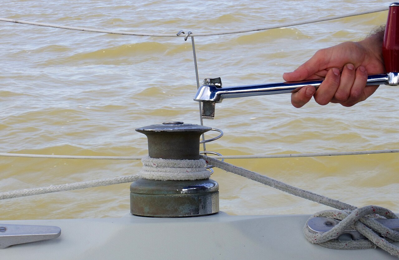 A winch with rope wrapped clockwise and the winch handle being taken out of its socket